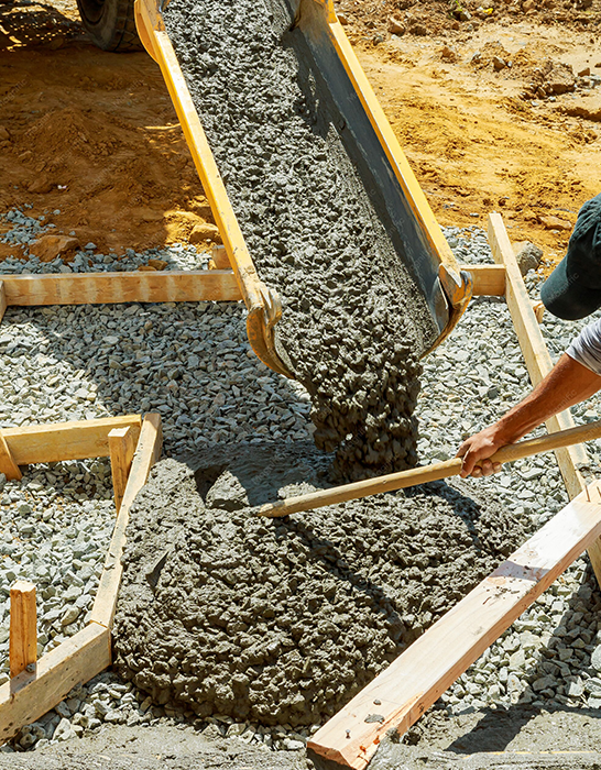 Worker Guiding Concrete Pouring into Wooden Frame for Sidewalk Installation