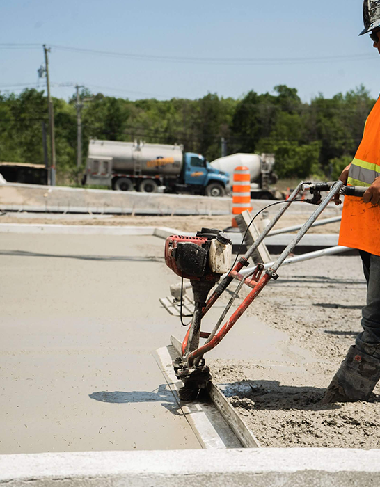 Worker Smoothing Fresh Concrete for Sidewalk Installation at Construction Site